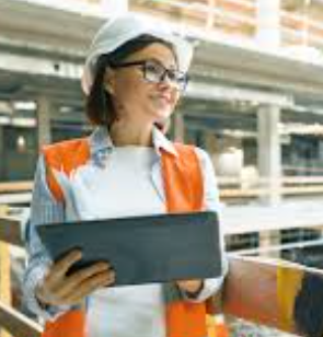 INtroverted woman in engineering - that is a woman in a hard hat, yellow high vis, smiling, holding a tablet